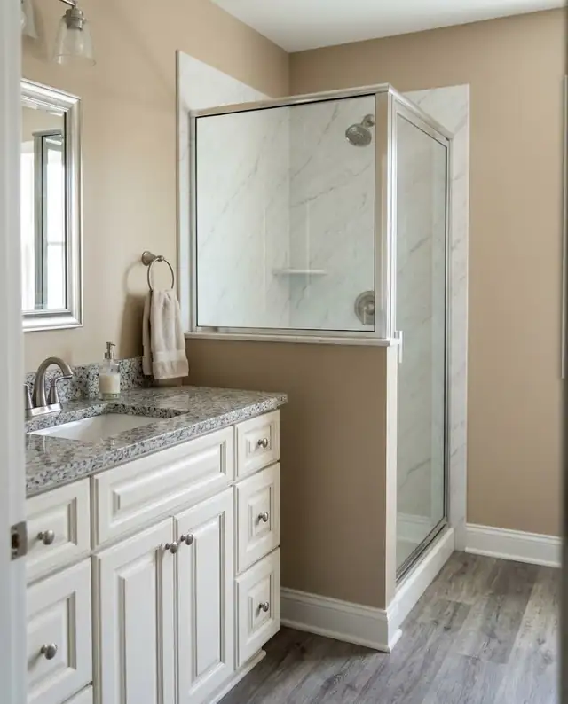 Bathroom corner with a white vanity beside a marble-look shower